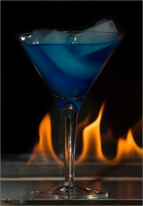 Blue cocktail with fire behind