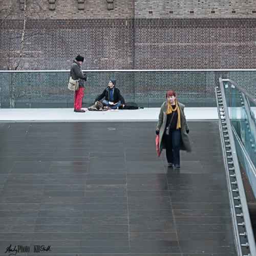 Homeless person, one person engaged with him, another walking by