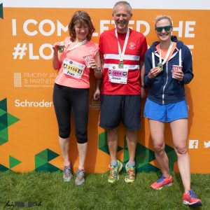Three runners in front of a promotional board