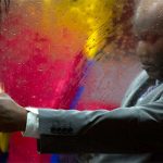 Man of colour in suit on a bus in the rain at night