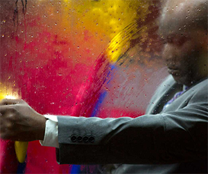 Man of colour in suit on a bus in the rain at night