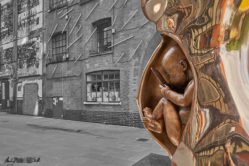 Golden sculpture depicting how tomorrow's children will be born into a connected world. Street shown in black and white