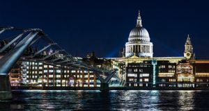 Grainy night time shot over the river Thames in London of the Millennium Bridge and St Pauls illuminated by spotlights