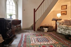 Main room view with fire, stairs and dog under stairs Landmark Trust County Antrim Northern Ireland