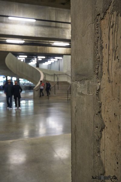 Distressed concrete wall with people and staircase in background