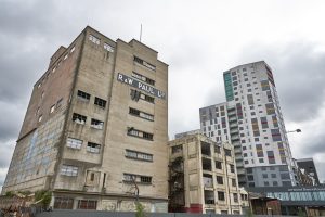 Dilapidated building with modern tower block behind