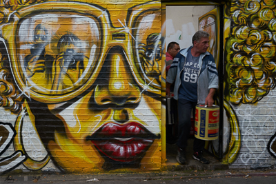 Two shifty looking characters leaving business premises through a door which is part of a large graffito in Brick Lane London