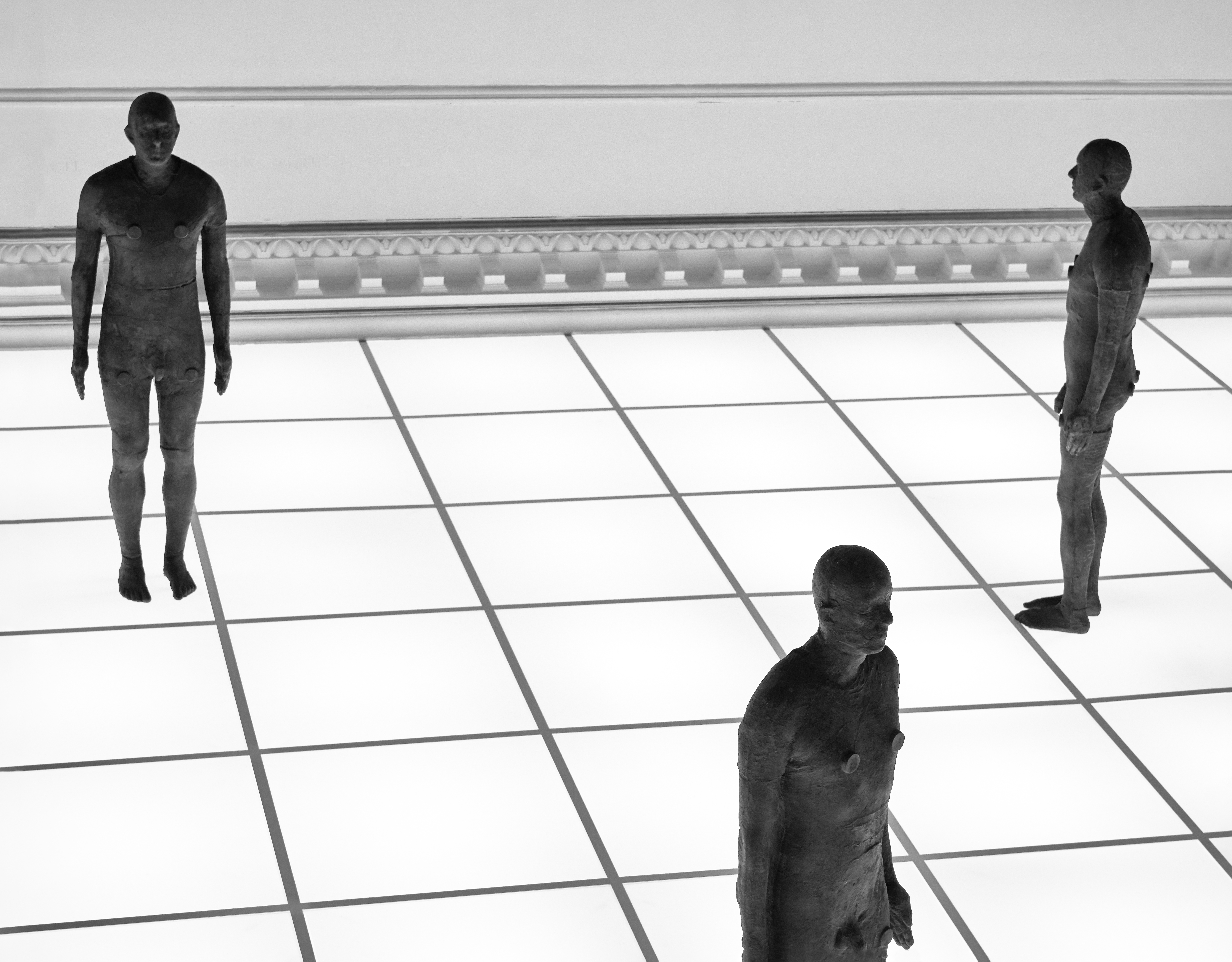 Three castings by Antony Gormley on an illuminated floor